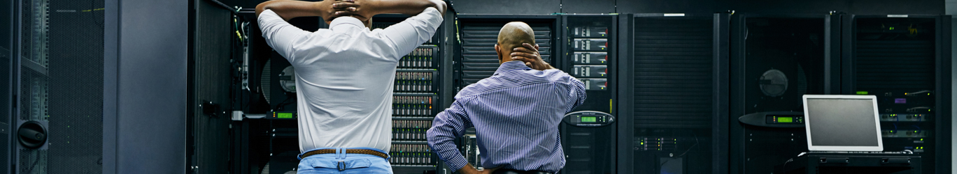 Two IT technicians repairing a computer in a data center.